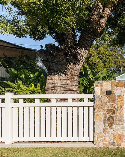 White contemporary timber fence featuring stone pillar entry