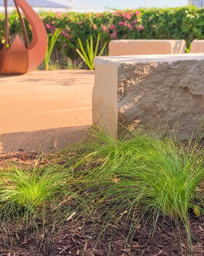 Rusted steel fire pit with large sandstone block seating and native grasses