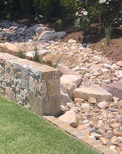 Dry creek bed solution for overland flow using tumbled sandstone rocks